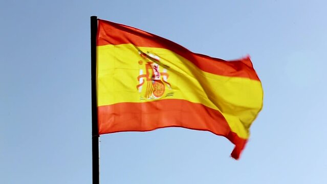 The national flag of Spain waving with slow motion in a blue sky