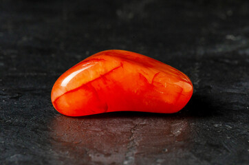 Carnelian mineral on a black concrete background. The concept of using minerals and crystals in...