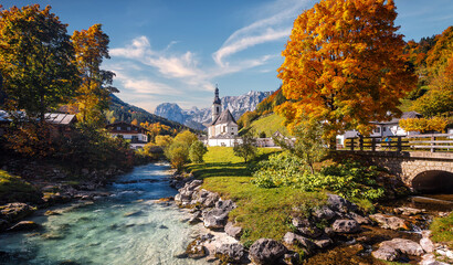 Beautiful nature landscape. Incredible autumn scenery. Scenic mountain landscape in the Bavarian Alps. Small church on the river bank.view on famous Parish Church of St. Sebastian - 525366013