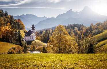 Fototapeta premium Beautiful nature landscape. Incredible autumn scenery. View on Alpine highlands with Watzmann mount, colorful trees and Small church. Famous Maria Gern Church. Berchtesgaden Bavaria Alps Germany