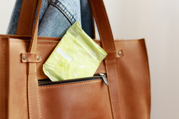 close-up of a woman's brown bag with a menstruation pad in a pocket