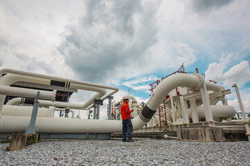 Male worker inspection at steel long pipes and pipe elbow in station oil factory during refinery...