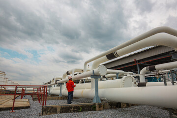 Male worker inspection at steel long pipes and pipe elbow in station oil factory during refinery...
