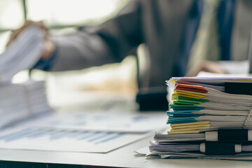 Businessman working in financial accounting with piles of documents on the desk at home work from home concept, business report, pile of unfinished paperwork