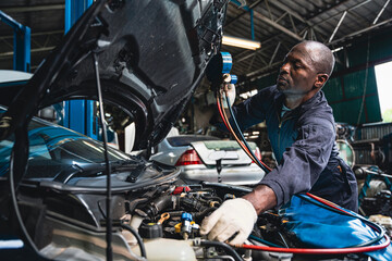 Male mechanic wearing a uniform maintaining the car air conditioner.