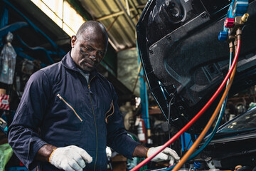 Male mechanic wearing a uniform maintaining the car air conditioner.