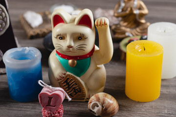 Fortune cat with two decorative candles on a wooden table