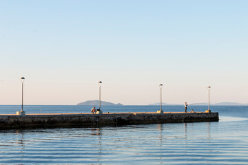 Obraz premium The pre-dawn twilight of the pier. Lamps at sea on the embankment