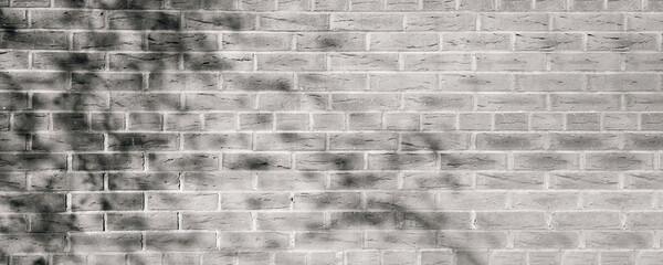 Black and White grunge brick wall with light and shadow of branches leaves background,  Vintage Texture of old wall in wide panoramic background image for use on web banner design
