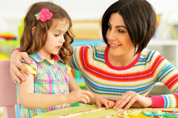 Cute little girl with her mother studying