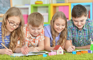 Fototapeta premium Children lying on floor drawing with pencils