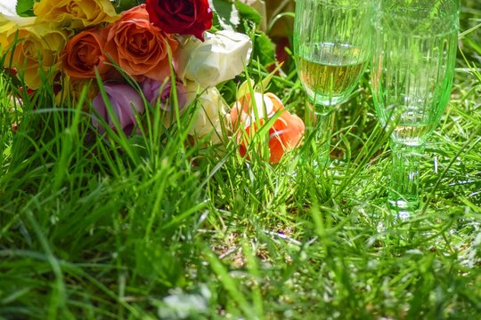Im Gras stehen Sektgl&auml;ser und ein Blumenstrau&szlig; zu einem besonderen Anlass