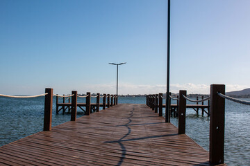 Obraz premium Wooden pier with lampposts at Sao Pedro da Aldeia beach on a sunny day, Cabo Frio, Brazil.