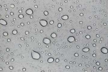 Regentropfen auf einer grauen Zeltplane