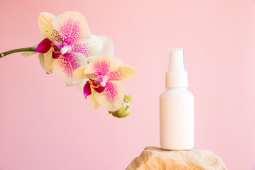 Obraz na płótnie Canvas Mockup white cosmetic spray mini travel bottle on stone and phalaenopsis orchid Octopus flowers on pink background. Body mist, sanitizer, perfume, sunscreen oil. Front view, blank bottle, template.