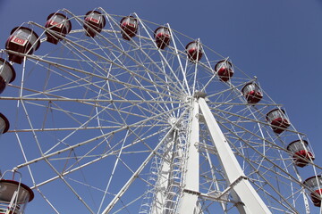 Big Ferris wheel on a blue sky background at sunny day closeup