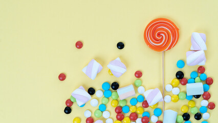 Mix of sweets - lollipop, sweets, marshmallows on a yellow background with a place under the text