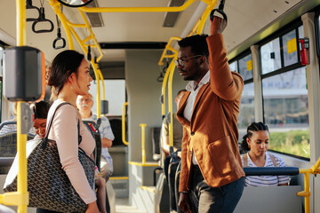 Black businessman and asian woman talking on bus