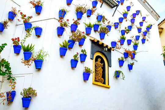 Poble Espanyol tourist attraction old narrow street with white walls decorated with blue flower pots in traditional andalusian style