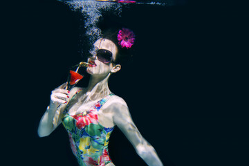 beautiful woman in a colourful stylish swimsuit and sunglasses and pink gerbera in the head with a...