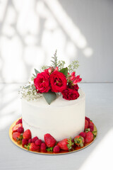 Obraz na płótnie Canvas Naked white cake with red flowers topper