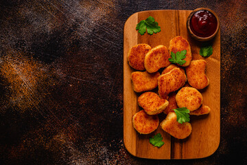 Fried crispy chicken nuggets on a wooden serving board.
