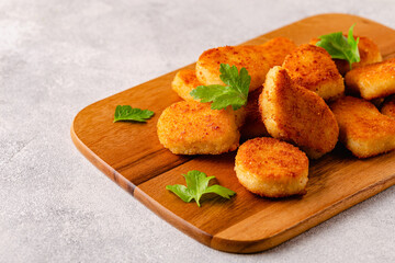 Fried crispy chicken nuggets on a wooden serving board.