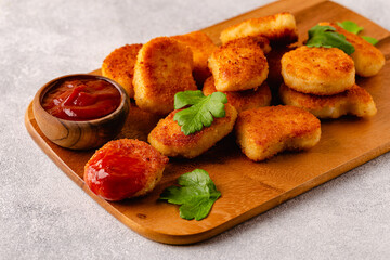 Fried crispy chicken nuggets on a wooden serving board.