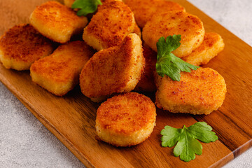 Fried crispy chicken nuggets on a wooden serving board.
