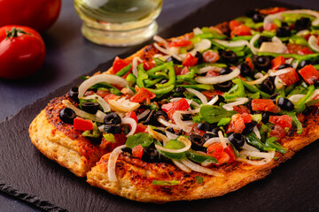 Homemade vegan pizza with tomatoes, peppers, olives, onions.