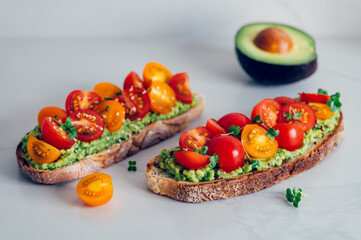 Tasty open sandwich from toasted sourdough bread with mashed avocado and fresh tomatoes