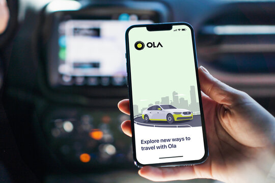 Girl inside car holding smartphone with Ola Cabs app on screen. Rio de Janeiro, RJ, Brazil. August 2022