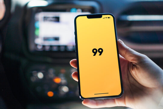 Girl inside car holding smartphone with 99 app on screen. Rio de Janeiro, RJ, Brazil. August 2022