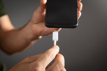 Man connecting charger cable to mobile phone.