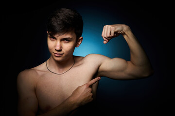 a healthy athletic teenager shows off his body against a dark background, the concept of proper nutrition