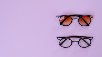 Eyeglasses and sunglasses on a purple background with space for text
