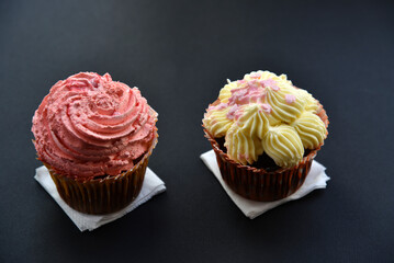 Sweet cakes with cream and sprinkles on a black background. Delicious pies for breakfast on black.