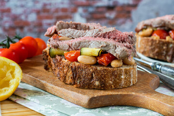 Beef steak on sourdough with garlicky tomatoes, courgettes and cannellini beans
