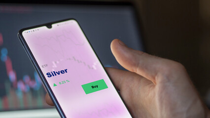 An investor's analyzing the silver etf fund on screen. A phone shows the ETF's prices silver fund...