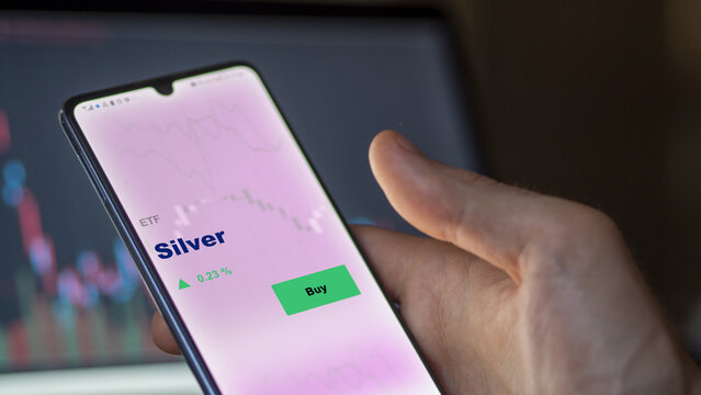 An Investor's Analyzing The Silver Etf Fund On Screen. A Phone Shows The ETF's Prices Silver To Invest