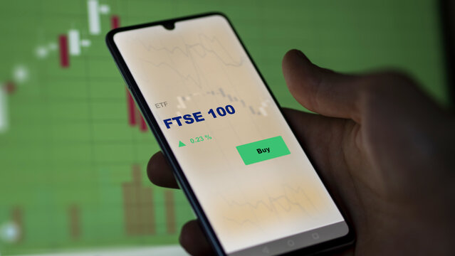 FTSE 100 etf fund on screen. A phone shows the FTSE 100 ETF's prices to invest