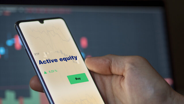 An investor's analyzing the active equity etf fund on screen. A phone shows the active equities ETF's prices to invest