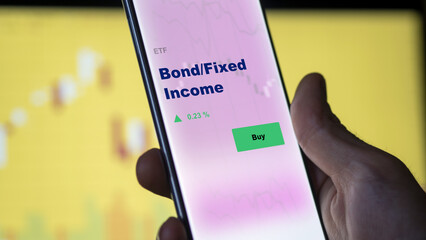 Bond fixed income An investor's analyzing the bond / fixed income etf fund on screen. A phone shows the ETF's prices stocks to invest