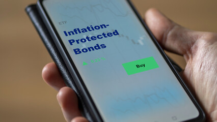 An investor's analyzing the inflation-protected bonds etf fund on screen. A phone shows the ibond ETF's prices  to invest