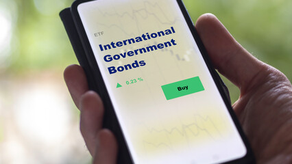 An investor's analyzing the international government bonds etf fund on screen. A phone shows the ETF's prices consumer discretionary equity to invest