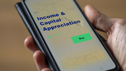 An investor's analyzing the income & capital appreciation etf fund on screen. A phone shows the...