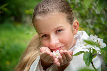  portrait of a little blond cute girl with long hair in white coat and with in white apple flowers