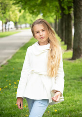 portrait of a little  beautiful  girl with long blond hair in the green park on sunny spring day