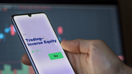 An investor's analyzing the trading inverse equity compliant investing etf fund on screen. A phone shows the ETF's prices stocks to invest.