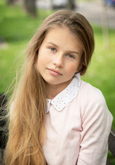 portrait of a little  beautiful  girl with long blond hair in the green park on sunny spring day
